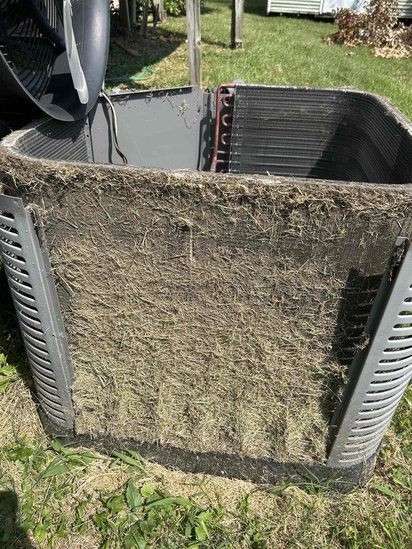Responded to no cooling complaint on 4-year-old electric HVAC system with indoor temperature reading 87°F against thermostat setpoint of 80°F. Upon inspection, discovered outdoor condenser unit with severely restricted airflow due to extensive debris accumulation on condenser coil and protective grilles. Filter screens were completely obstructed with matted grass clippings, dirt, dust, and organic material buildup, preventing proper heat exchange and causing system to run continuously without adequate cooling capacity. Removed access panels and extracted heavy layer of compacted debris from condenser coil fins and surrounding protective screens. Cleaned condenser coil thoroughly to restore airflow and heat transfer efficiency. Inspected fan motor operation and verified proper rotation. Noted indoor air filter in crawlspace location had not been changed since system installation in May 2022, contributing to overall system inefficiency. Recommended immediate replacement of 16x20x4 indoor