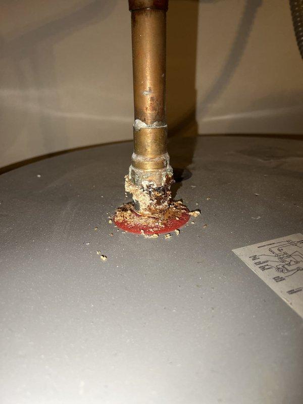 Conducted comprehensive assessment of residential tanked water heater following improper installation by previous contractor. Inspection revealed severe corrosion at base connections and pipe penetration points, with extensive mineral buildup and oxidation damage to copper piping and floor surfaces. Documented corroded plumbing connections at water heater top, including compromised brass fittings and deteriorated pipe joints where improper installation techniques had accelerated corrosion. Photographed evidence of water damage, rust staining, and structural deterioration at floor level. Evaluated condition of electrical connections, safety valves, and overall system integrity to determine viability of repair versus full unit replacement. Provided detailed estimate options for corrective action to address failed connections and restore system to code-compliant operation.