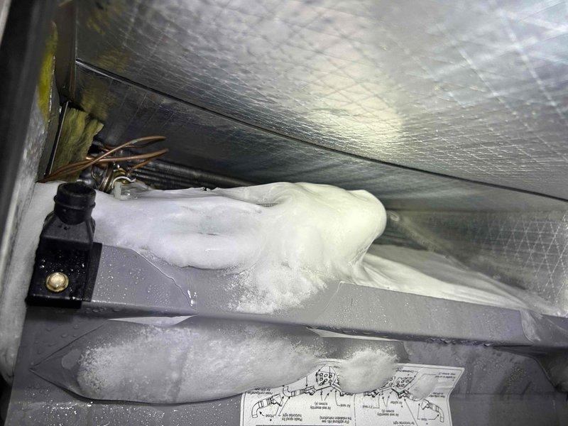 Responded to service call back for system freezing and inadequate cooling. Upon inspection, found evaporator coil drain pan with excessive condensate overflow and suds buildup, indicating clogged condensate drain line. Cleared drain line obstruction, flushed system, and verified proper drainage. Inspected air filter condition in basement mechanical room and confirmed adequate airflow. System tested and operating within normal parameters with proper condensation drainage restored.