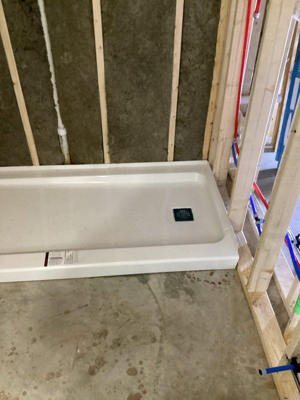 Completed comprehensive plumbing rough-in installation for two bathroom renovation project. Installed new sewage ejector pump and verified proper functionality before departure.

**Bathroom A (Shower):**
Jackhammered concrete flooring to access drainage area. Installed new P-trap assembly with stub-up for shower base connection. Ran and stubbed out Uponor water supply lines for lavatory, toilet, and shower connections. Installed Delta universal rough-in shower valve with Uponor fittings per specifications.

**Bathroom B (Tub & Shower):**
Ran complete Uponor water supply lines for lavatory, toilet, and tub/shower valve connections. Installed Delta universal rough-in tub/shower valve with Uponor fittings. Set new shower base and installed tub/shower wall panels. Ran stub-out for lavatory drain connection.

All water supply lines installed using new Uponor PEX piping system with hot and cold lines properly color-coded and secured to framing. All rough-in valves and drain connections teste