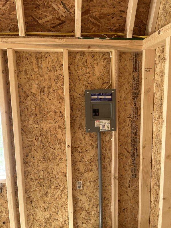 Completed full electrical wiring installation in 10x26 outbuilding structure, installing 100-amp main service panel with breakers, GFCI outlet, duplex receptacles, single-pole switch, and keyless light fixture with bulb. Ran all necessary branch circuits through exposed framing, mounted panel centrally on OSB wall with proper conduit connections, and installed outlet boxes per code requirements. All electrical components tested and verified operational upon completion.