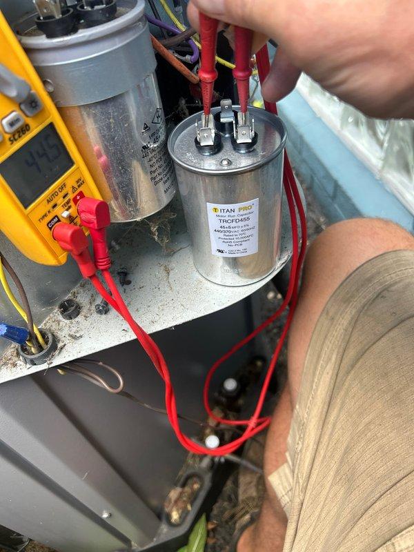 Responded to service call for outdoor HVAC unit producing abnormal loud noise while system remained operational. Performed comprehensive electrical diagnostics on condensing unit, utilizing digital multimeter to test capacitor functionality and verify proper voltage readings across terminals. Testing revealed capacitor measurements at 9.02 microfarads, indicating potential degradation from rated specifications. Inspected all electrical connections, wiring terminals, and associated components for signs of failure or loose connections that could contribute to noise generation. Documented equipment conditions through diagnostic photography for service records.