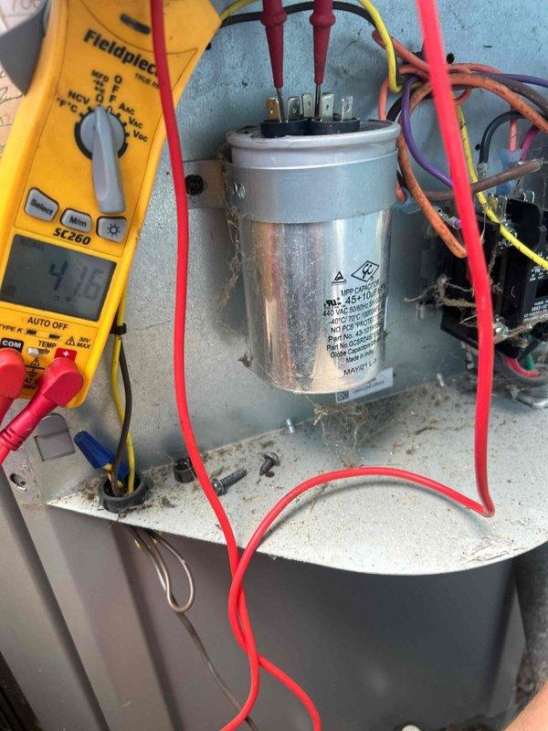 Responded to service call for outdoor HVAC unit producing abnormal loud noise while system remained operational. Performed comprehensive electrical diagnostics on condensing unit, utilizing digital multimeter to test capacitor functionality and verify proper voltage readings across terminals. Testing revealed capacitor measurements at 9.02 microfarads, indicating potential degradation from rated specifications. Inspected all electrical connections, wiring terminals, and associated components for signs of failure or loose connections that could contribute to noise generation. Documented equipment conditions through diagnostic photography for service records.