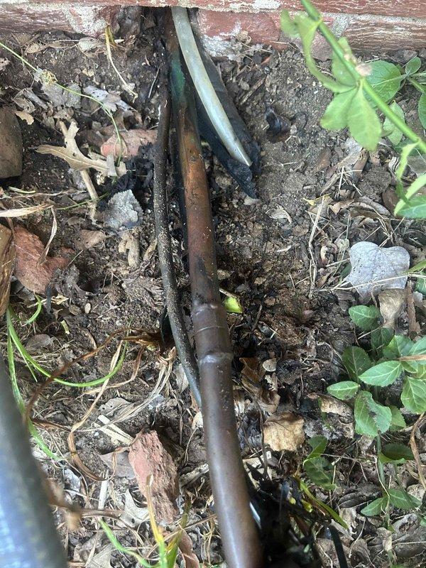 Responded to no-cooling complaint on one-year-old air conditioning system. Upon arrival, conducted visual inspection of outdoor condensing unit and associated refrigerant lines. Unit appeared properly installed on concrete paver pad with appropriate clearances. Observed significant corrosion on refrigerant line set entering crawlspace, indicating potential leak point. Corroded piping showed advanced oxidation consistent with moisture exposure and inadequate line protection. Performed system diagnostics and identified refrigerant leak at corroded section of line set. Repaired leak, evacuated system, and recharged to manufacturer specifications. Verified proper system operation with normal temperature differential and adequate airflow. Unit restored to full cooling capacity.