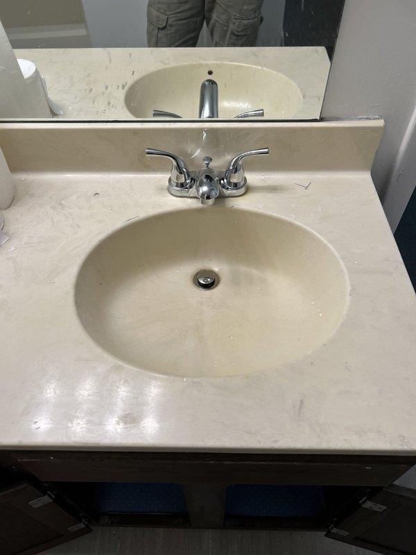 Replaced two customer-supplied chrome centerset lavatory faucets in vacant property bathroom. Both faucets were two-handle models with lever-style handles and curved spouts, installed on beige cultured marble vanity tops with integrated oval basins. Completed installations per manufacturer specifications and verified proper operation and leak-free connections.