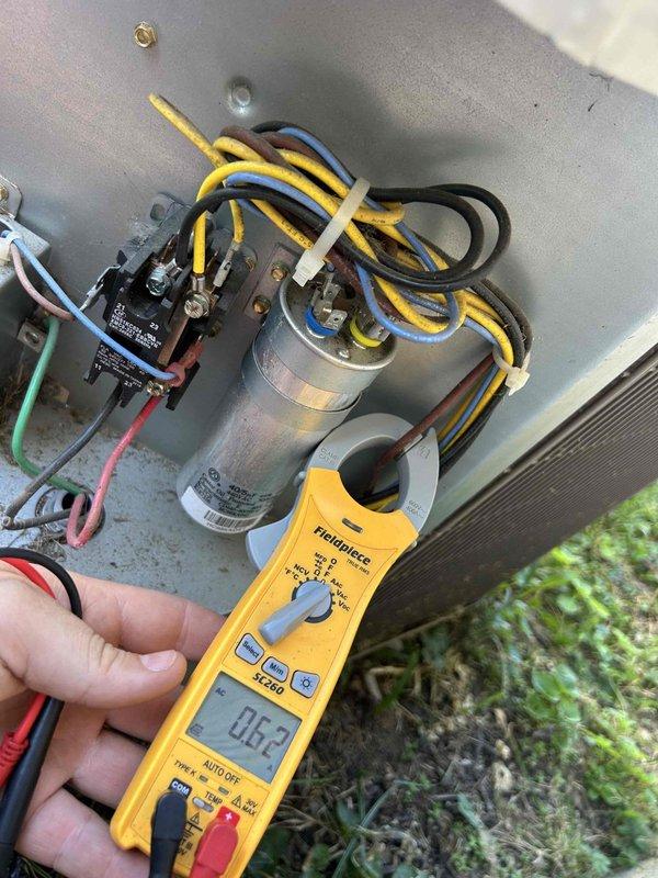 Responded to no-cooling call on 6-year-old electric HVAC system. Upon arrival, found thermostat display was blank due to depleted batteries, which were replaced to restore display functionality. Proceeded with diagnostic testing of outdoor condensing unit. Using digital clamp meter, measured microamp reading of 0.62 at the capacitor, indicating failed run capacitor preventing compressor and condenser fan motor operation. Inspected dual run capacitor and associated contactor wiring connections. Verified all electrical connections were secure with proper wire terminations to capacitor terminals and contactor. Inspected indoor air handler unit located in attic space, noting dirty air filter requiring replacement. Confirmed ductwork and electrical connections at indoor unit were intact. Recommended capacitor replacement to restore cooling operation and immediate filter replacement to ensure proper airflow and system efficiency.