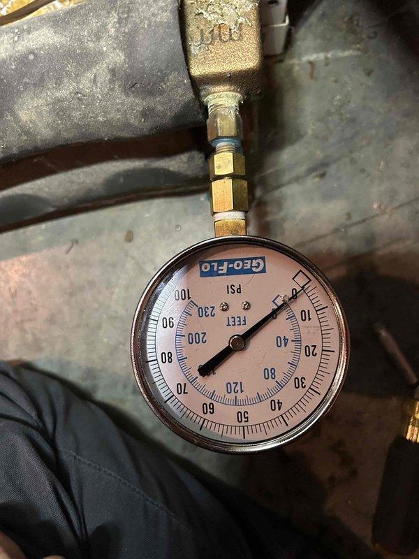 Responded to service call for 18-year-old geothermal system not maintaining desired temperature, getting within 4 degrees of setpoint. Performed diagnostic evaluation of basement-located air handler and geothermal loop system, inspecting refrigerant lines, pressure readings on loop system gauge, and overall equipment condition. Documented system pressures and visual condition of equipment with photos showing Geo-Flo pressure gauge readings and insulated refrigerant line configuration on air handler unit.