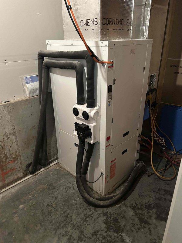 Responded to service call for 18-year-old geothermal system not maintaining desired temperature, getting within 4 degrees of setpoint. Performed diagnostic evaluation of basement-located air handler and geothermal loop system, inspecting refrigerant lines, pressure readings on loop system gauge, and overall equipment condition. Documented system pressures and visual condition of equipment with photos showing Geo-Flo pressure gauge readings and insulated refrigerant line configuration on air handler unit.