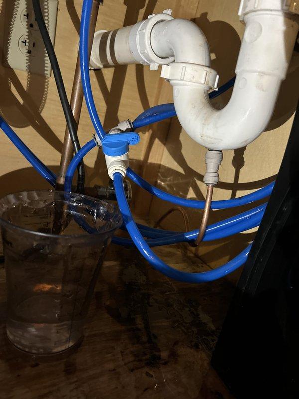 Responded to report of water leak in basement originating from kitchen area above. Upon inspection of under-sink plumbing, identified source of leak at P-trap connection beneath kitchen sink. Found loose compression fitting on PVC drain assembly allowing water to escape during sink usage. Tightened P-trap connections and verified proper seal at all joints. Inspected garbage disposal connections and water supply lines, including blue flex lines and shutoff valves, confirming no additional leak points. Examined three-stage water filtration system mounted in cabinet, verified all filter housings secure with no signs of leakage. Ran water through sink and disposal system to test repairs and confirm leak resolution. Advised homeowner to monitor basement area for any recurrence and explained importance of periodic inspection of drain connections to prevent future issues.
