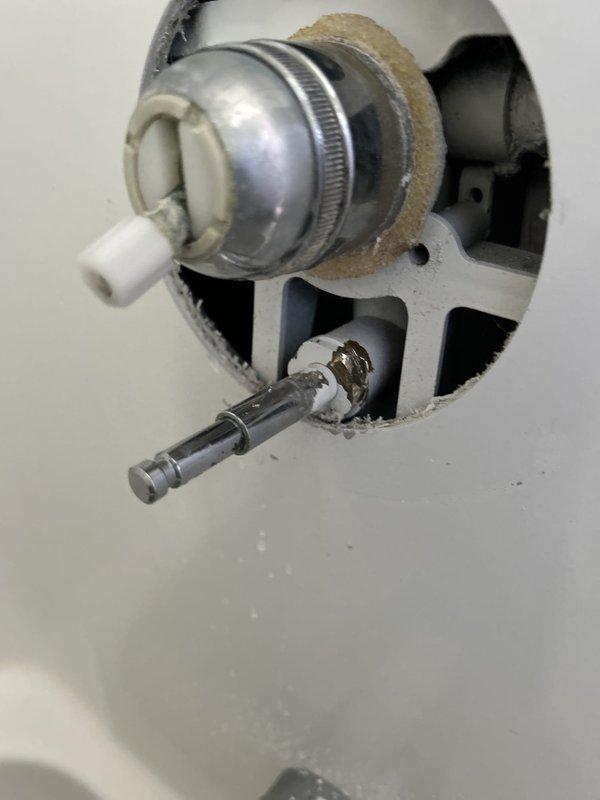 Responded to guest bathroom shower valve issue where water was leaking from the handle assembly when shower was activated. Upon inspection, identified compromised valve stem seal and escutcheon assembly allowing water to bypass through the handle mechanism rather than directing flow properly through the spout and diverter. Disassembled single-handle shower control valve, examined internal components including cartridge, stem seals, and trim assembly. Documented existing fixture condition showing brushed metal escutcheon with clear acrylic handle and gray tub spout with diverter below. Assessed valve cartridge for wear and proper seating within the rough-in body to determine repair feasibility versus full replacement recommendation.