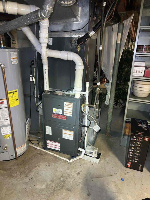 Responded to no cooling complaint on 2-year-old electric HVAC system with indoor temperature exceeding 80 degrees. Upon arrival, performed diagnostic assessment of Goodman furnace and air handler unit located in basement utility area. Inspected outdoor condensing unit, electrical connections, and associated components. Verified power supply to both indoor and outdoor equipment, checked refrigerant lines, and assessed airflow from supply vents. Documented equipment condition through photographic records of both exterior condensing unit installation and indoor air handler configuration. System evaluated for proper operation of compressor, fan motor, and control circuits to identify root cause of cooling failure.
