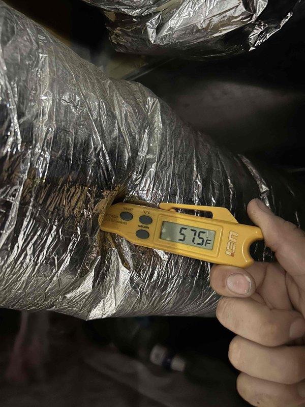 Responded to no cooling call on 15-year-old electric heat pump system with no airflow from indoor unit located in crawlspace. Upon arrival, confirmed thermostat was receiving power but blower motor was not operating. Performed diagnostic inspection of air handler and verified no tripped breakers, refrigerant line icing, or obvious electrical issues at disconnect. Accessed crawlspace unit and tested system components. Measured supply air temperature at ductwork registering 57.5°F, indicating compromised system performance. Blower motor failure identified as root cause of no airflow condition, requiring replacement to restore system operation.