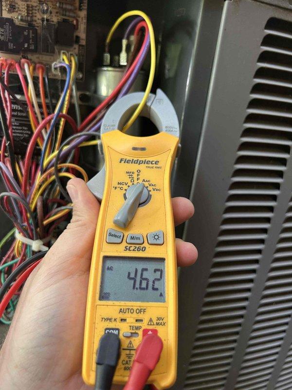 Responded to no cooling call on 10-year-old electric HVAC system with no airflow and indoor temperature at 80 degrees. Upon arrival, performed diagnostic testing of outdoor unit components using clamp meter, which revealed amperage reading of 46.2 amps at compressor. Inspected refrigerant line connections, capacitor, and electrical control board wiring. Identified system failure preventing compressor operation and airflow circulation. Documented equipment condition with photos showing outdoor unit internal components, refrigerant line connections with brass fittings, and electrical measurements during troubleshooting process.
