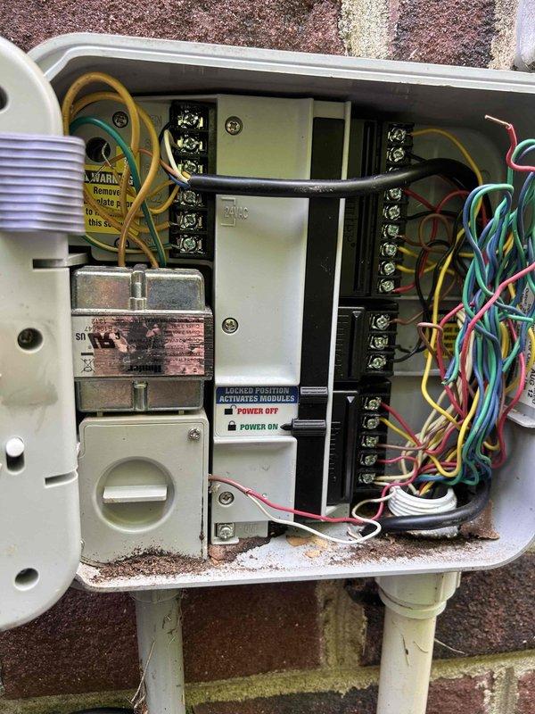 Responded to service call for non-functioning irrigation system and flickering landscape lighting. Diagnosed electrical issues in irrigation control panel and timer system. Found heavily corroded terminal blocks and oxidized brass terminals in outdoor junction boxes affecting system operation. Inspected control module, relay components, and terminal connections showing significant weathering and debris accumulation. Addressed wiring connections and electrical components to restore proper function to irrigation system and landscape lighting zone.