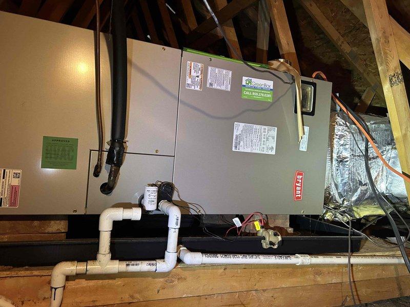 Responded to no cooling complaint on second floor system installed in 2018. Inspected attic-mounted air handler unit and associated components including condensate drainage system, refrigerant lines, and ductwork. Verified equipment installation and documented current condition of HVAC system with exterior condensate discharge line showing signs of debris accumulation at roof edge termination point.