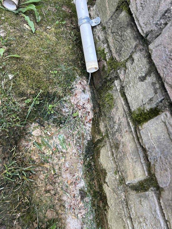 Responded to no cooling complaint on second floor system installed in 2018. Inspected attic-mounted air handler unit and associated components including condensate drainage system, refrigerant lines, and ductwork. Verified equipment installation and documented current condition of HVAC system with exterior condensate discharge line showing signs of debris accumulation at roof edge termination point.
