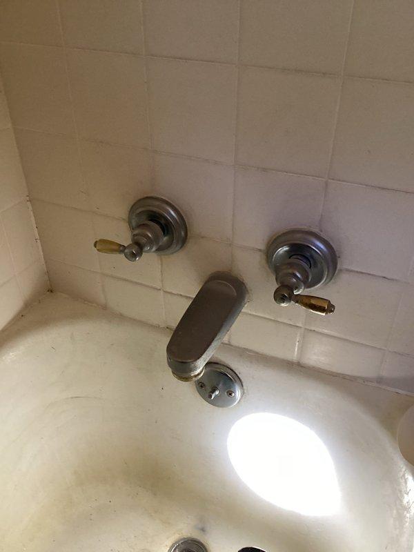 Responded to service call for dripping tub/shower valve. Accessed plumbing through hallway panel behind shower wall. Inspected copper supply lines and valve assembly beneath structure, measuring pipe configurations and assessing existing fixtures. Evaluated aged brass shower valve, tub spout, and control valves showing significant wear and tarnishing. Determined valve required full replacement rather than rebuild due to condition. Replaced defective shower valve assembly with new unit, ensuring proper connections to existing copper supply lines. Tested system for leaks and verified proper operation of all controls.