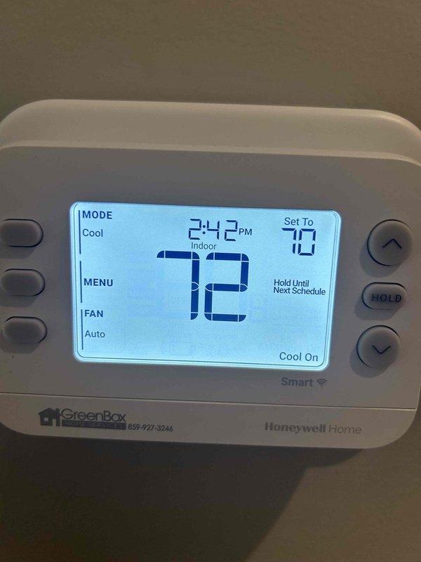 Responded to no cooling complaint on 1-year-old geothermal system with indoor temperature at 76°F despite thermostat set to 72°F. Upon arrival, verified Honeywell Home smart thermostat displaying "Cool On" mode with system actively calling for cooling. Inspected indoor unit located on main floor and examined air handler components. Photographed curved metallic heat exchanger coil showing uniform grid pattern with no visible damage or debris accumulation. Confirmed thermostat programming and hold settings were properly configured with system attempting to maintain setpoint temperature. System appeared to be running but not achieving desired cooling capacity.