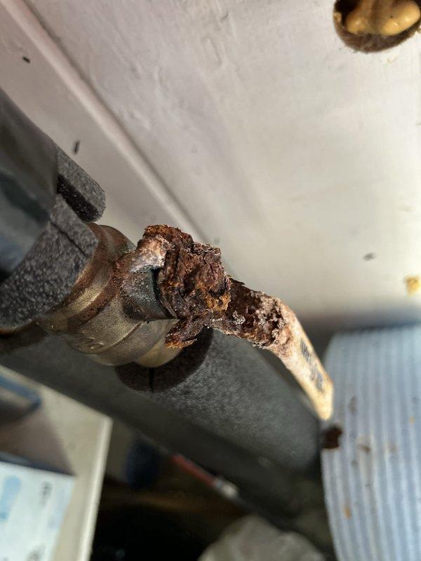 Performed routine maintenance flush on a 9-year-old gas tankless water heater located in carport. Connected circulation pump and hoses to service valves and flushed unit with descaling solution to remove mineral buildup and maintain optimal heat exchanger performance. During inspection, identified significant corrosion on copper pipe connections and fittings near the unit, indicating potential moisture exposure and oxidation over time. Completed flush cycle, verified proper flow rates, and documented corroded plumbing components for future repair consideration.