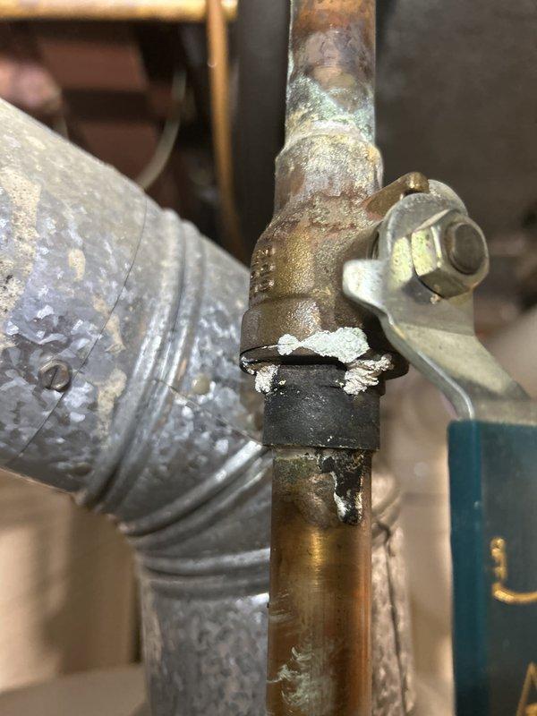 Completed comprehensive 65-point whole home plumbing inspection per preventive service agreement protocol. Conducted thorough assessment of all accessible plumbing components, fixtures, supply lines, drain systems, and shut-off valves throughout the property. Documented significant corrosion and oxidation on main water supply valve assembly, noting advanced deterioration with greenish-blue patina indicating long-term moisture exposure. Identified compromised rubber coupling on copper pipe joint showing degradation and tearing, requiring future replacement to prevent potential leaks. Observed extensive mineral buildup and oxidation on adjacent ductwork and piping. Photographed all findings for maintenance records. All observations reported to property owner with recommendations for addressing corroded components to maintain system integrity.