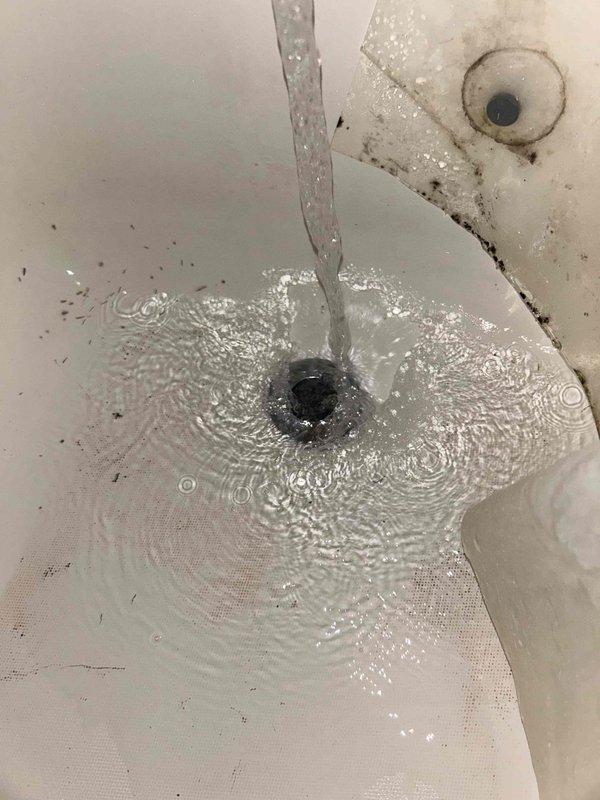 Responded to multi-service plumbing call addressing issues in both bathrooms. Inspected master bathroom toilet for intermittent running condition and assessed tank components for wear and malfunction. Examined hall bathroom toilet tank with active leak at rear of tank, documented significant mineral deposits and internal staining affecting tank integrity. Evaluated hall shower with dripping showerhead requiring washer or cartridge replacement. Assessed tub drain with backup issue indicating partial obstruction in drain line. Documented existing conditions through photography showing deteriorated flush valve assembly, corroded tank components, and mineral buildup throughout affected fixtures. Provided assessment and recommendations for necessary repairs including tank seal replacement, flush valve rebuild, showerhead repair, and drain cleaning service to restore proper function to all affected plumbing fixtures.