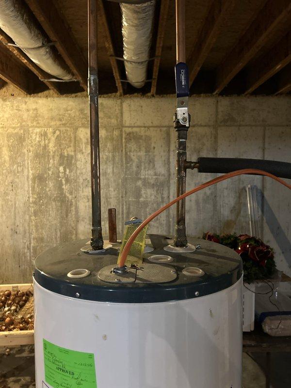 Completed installation of electric tanked water heater in basement location. Removed existing unit and installed new white tank-style electric water heater with proper plumbing connections including cold water inlet and hot water outlet piping. Connected pressure relief valve with discharge piping, installed shut-off valves, and established electrical connections to unit. All copper and flexible supply lines secured and tested for proper operation. Unit positioned on concrete floor with adequate clearance for ventilation and future maintenance access. System tested and verified for proper heating function and absence of leaks at all connection points.