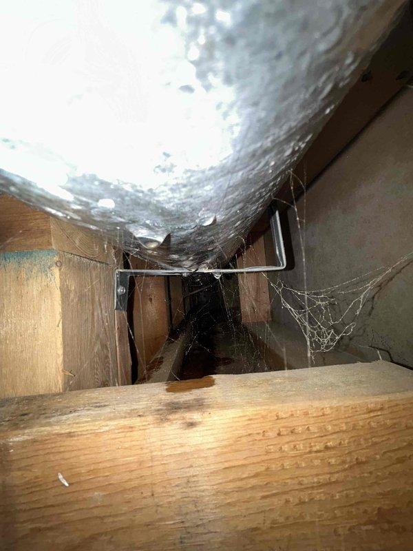 Accessed attic space through existing ceiling opening to address unsealed and uninsulated ductwork. Removed existing cobwebs and debris from work area. Applied foil tape to all duct seams and joints to eliminate air leakage. Wrapped cylindrical supply duct with R8 foil-backed insulation material, securing with additional foil tape at all seams for proper adhesion and thermal performance. Modified drywall access opening as needed to facilitate complete ductwork treatment. Restored work area and ensured all insulation joints were properly sealed to prevent condensation and improve system efficiency.