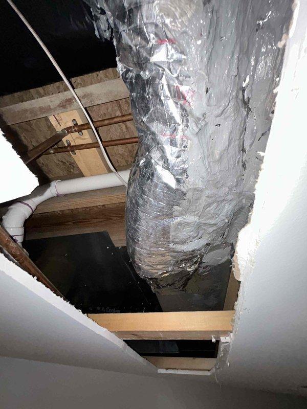 Accessed attic space through existing ceiling opening to address unsealed and uninsulated ductwork. Removed existing cobwebs and debris from work area. Applied foil tape to all duct seams and joints to eliminate air leakage. Wrapped cylindrical supply duct with R8 foil-backed insulation material, securing with additional foil tape at all seams for proper adhesion and thermal performance. Modified drywall access opening as needed to facilitate complete ductwork treatment. Restored work area and ensured all insulation joints were properly sealed to prevent condensation and improve system efficiency.