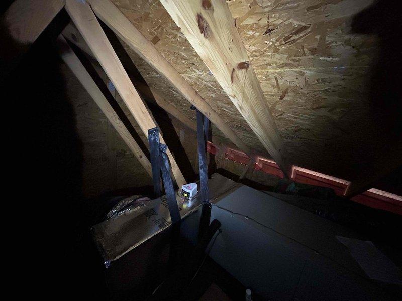 Completed management-requested return visit to attic for visual documentation of condensate line trap and installed additional hanger support on return ductwork to prevent future collapse. Photographed existing condensate trap configuration and secured reflective-wrapped rectangular return duct with black strapping to maintain proper positioning and structural integrity.