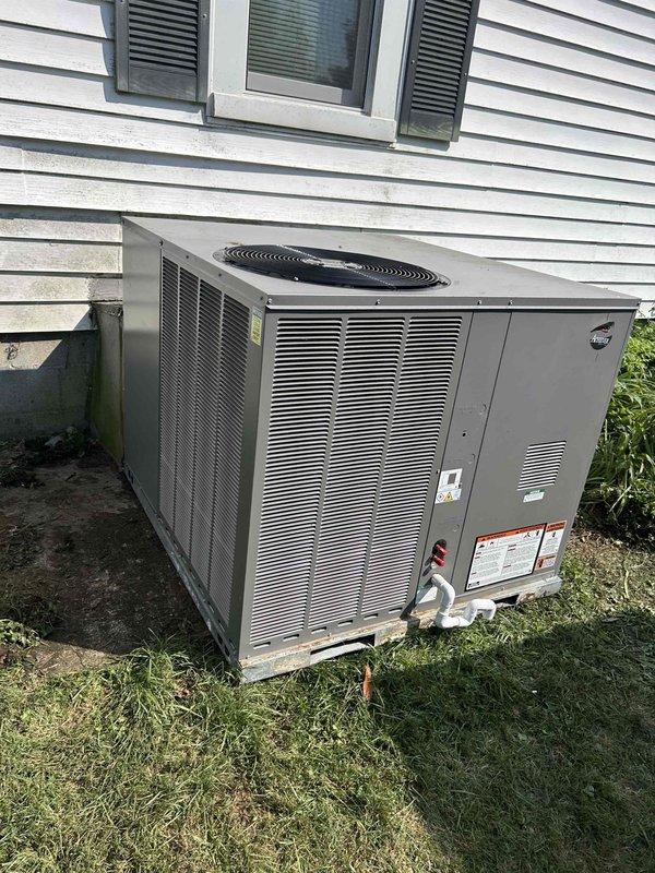 Completed installation of RUUD 4-ton gas package unit (model RGEAYB048AJT101NA) on residential property. Positioned unit on EL5060-3 concrete pad adjacent to structure, reused existing electrical whip while replacing disconnect box, and completed ductwork transition with protective cover. Installed digital thermostat and verified all system operations, with existing floor grille filters retained per specifications.