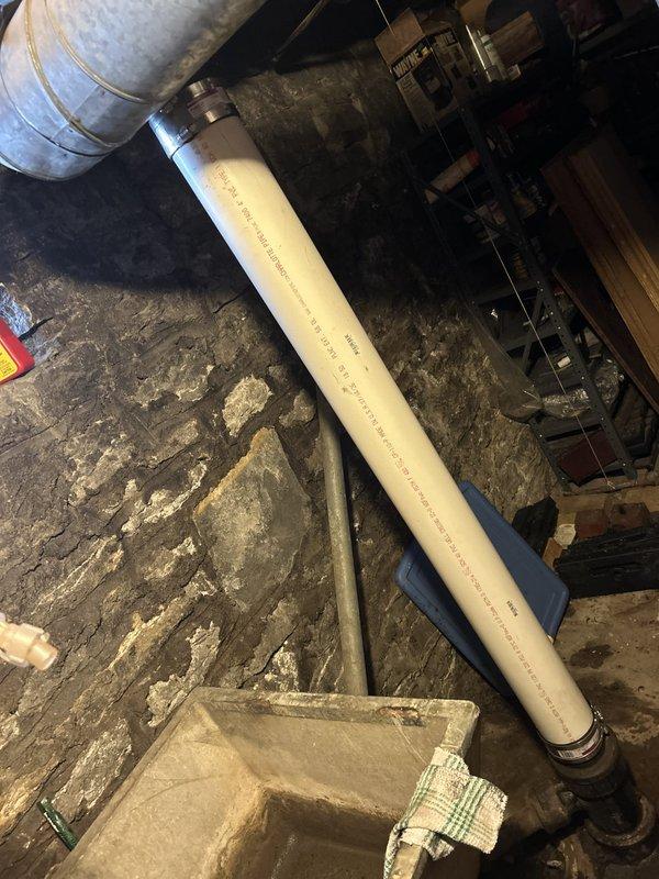 Responded to service call for leak in major bathroom pipe requiring inspection and estimate. Upon arrival, accessed unfinished basement area with exposed stone foundation to locate source of water intrusion. Conducted thorough inspection of vertical drainage system including large gray PVC piping running along foundation wall and cream-colored PVC pipe with metal clamps in crawl space area. Assessed condition of plumbing infrastructure, connections, and surrounding mechanical systems. Documented findings with photographs showing pipe configuration, mounting hardware, and basement environment for accurate estimate preparation. Provided customer with detailed assessment of leak location and recommended repair options for the affected drainage line.