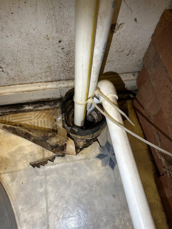 Performed camera inspection of basement floor drain as requested by HVAC technician to diagnose drainage issue. Inspected drain line using video camera equipment, documented existing plumbing configuration including vertical PVC drain pipes with zip-tie securing and rubber boot penetration through floor assembly. Observed signs of moisture and debris accumulation around drain area, with visible wear and staining on surrounding surfaces indicating potential drainage concerns. Provided repair estimate based on camera inspection findings to address identified issues with drain system.