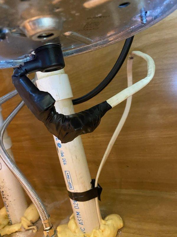 Responded to callback for improperly installed Whirlpool garbage disposal Model GC2000PE3 that was hardwired instead of utilizing the factory plug configuration, creating a potential fire hazard. Documented existing installation with photographs showing under-sink plumbing configuration, PVC drain assembly, supply lines, and disposal electrical connections for management review and assessment of corrective action needed.