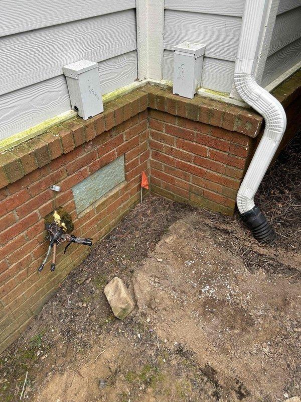 Recovered refrigerant from downstairs air conditioning system and removed the outdoor unit from the right side to allow for installation of a single large equipment pad for both condensing units. Sealed and labeled the refrigerant line set with tape, wire-nutted low voltage wiring to prevent electrical shorts, and hauled away the disconnected equipment. Tested downstairs gas furnace operation to verify proper system functionality following the removal work.