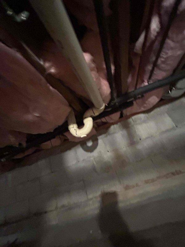 Responded to service call for drainage issue occurring during washing machine spin cycle, potentially related to previous clog. Accessed crawl space to inspect plumbing system and identify source of backup. Located and examined drainage lines serving laundry area, including PVC piping and connections between floor joists. Inspected pipe routing, fittings, and joints for blockages, improper slope, or structural issues affecting drainage flow. Assessed condition of existing plumbing infrastructure in confined space beneath structure. Documented findings with photos showing pipe configuration, insulation clearances, and overall system layout for customer records and future reference.