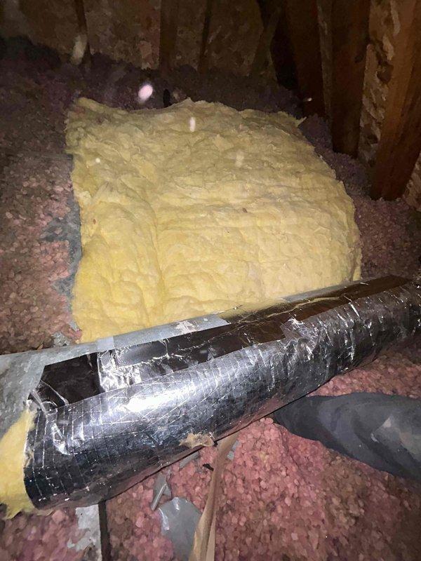 Wrapped two sections of exposed metal ductwork in the attic with foil-backed insulation to improve thermal efficiency and prevent condensation. The flexible duct sections showed signs of deterioration with damaged outer foil covering, which were addressed by applying proper insulation wrap over the affected areas.
