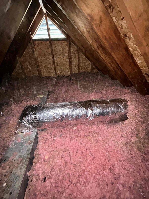 Wrapped two sections of exposed metal ductwork in the attic with foil-backed insulation to improve thermal efficiency and prevent condensation. The flexible duct sections showed signs of deterioration with damaged outer foil covering, which were addressed by applying proper insulation wrap over the affected areas.