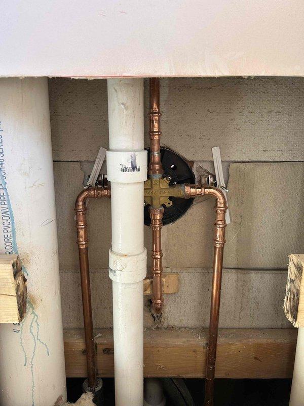 Removed existing shower valve by accessing the plumbing from behind the toilet through the wall. Installed customer-supplied shower valve and trim kit, connecting new copper supply lines to the main water system. Tested installation for proper operation and verified no leaks at connections.