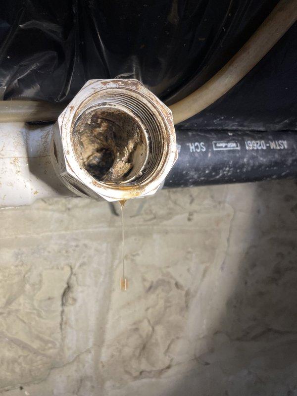 Responded to service call for clogged kitchen sink. Upon arrival, performed diagnostic assessment of drainage system. Inspected under-sink plumbing connections and discovered significant buildup and corrosion within pipe fittings and drainage components. Observed active water leakage from threaded union fitting, indicating compromised seal integrity. Noted mineral deposits and dark staining throughout interior pipe surfaces, consistent with long-term accumulation and restricted water flow.

Disassembled affected plumbing connections to access clog location. Cleared blockage from drainage line and removed accumulated debris from pipe interior. Addressed corroded threaded fitting showing deterioration and water seepage. Cleaned mineral deposits from connection points to ensure proper sealing upon reassembly. Verified all flexible hoses and rigid pipe connections for structural integrity and proper alignment.

Reassembled plumbing components with secure threaded connections. Tested draina