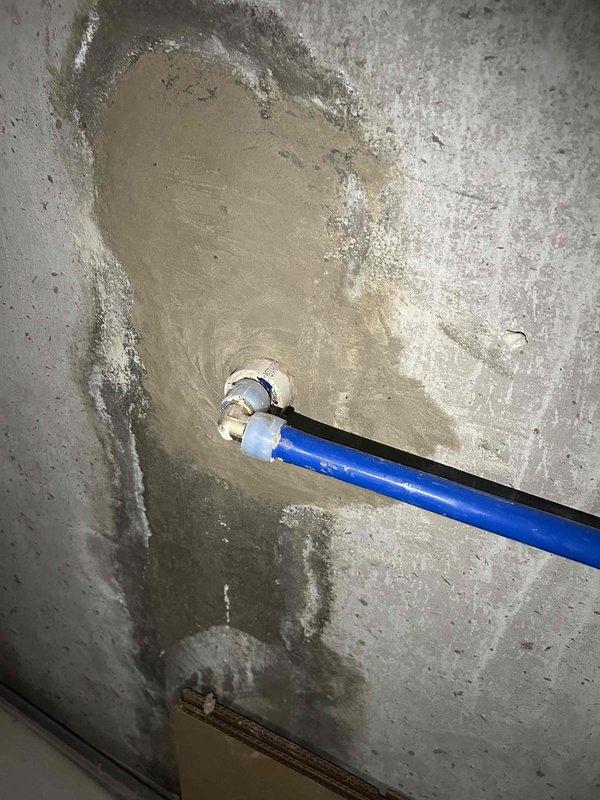 Responded to property for plumbing leak repair estimate following leak detection service confirmation. Leak source identified at blue plastic pipe penetration through concrete foundation wall, with extensive water damage, staining, and moisture infiltration evident around pipe entry point. Prepared estimate for excavation and repair of underground piping, requiring compact excavator equipment to access affected area beneath concrete and expose damaged pipe section for replacement and proper sealing of wall penetration.