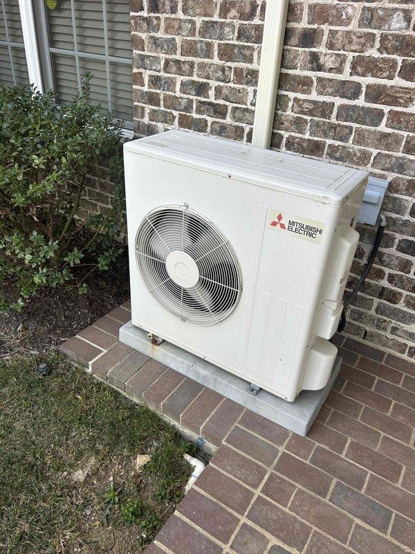 Completed comprehensive HVAC maintenance inspection under Club Duo service agreement for residential property equipped with 8-year-old geothermal water furnace and 8-year-old Mitsubishi Electric mini-split system serving basement and sunroom areas. Performed visual inspection of outdoor mini-split condenser unit, confirming proper installation on concrete pad with secure refrigerant line connections running up exterior brick wall, noting unit maintained in clean condition with no visible damage or deterioration. Conducted temperature verification of system performance using infrared thermometer, recording supply air temperature of 67.4°F at interior ceiling-mounted register to confirm proper heating operation and airflow distribution.