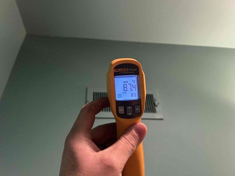 Completed comprehensive HVAC maintenance inspection under Club Duo service agreement for residential property equipped with 8-year-old geothermal water furnace and 8-year-old Mitsubishi Electric mini-split system serving basement and sunroom areas. Performed visual inspection of outdoor mini-split condenser unit, confirming proper installation on concrete pad with secure refrigerant line connections running up exterior brick wall, noting unit maintained in clean condition with no visible damage or deterioration. Conducted temperature verification of system performance using infrared thermometer, recording supply air temperature of 67.4°F at interior ceiling-mounted register to confirm proper heating operation and airflow distribution.