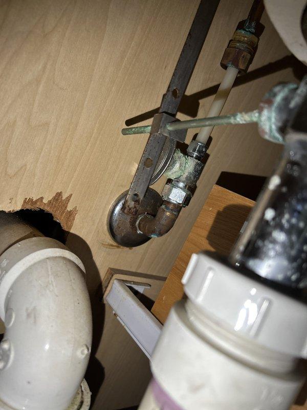 Completed comprehensive 65-point whole home plumbing inspection as requested. Inspection revealed significant corrosion and rust on main shutoff valve assembly and associated metal pipe fittings, indicating age-related deterioration that may require future attention. Under-sink plumbing system examined, including PVC drainage pipes, pump unit with auxiliary connections, and flexible supply lines, all found to be properly secured and functional at time of inspection.