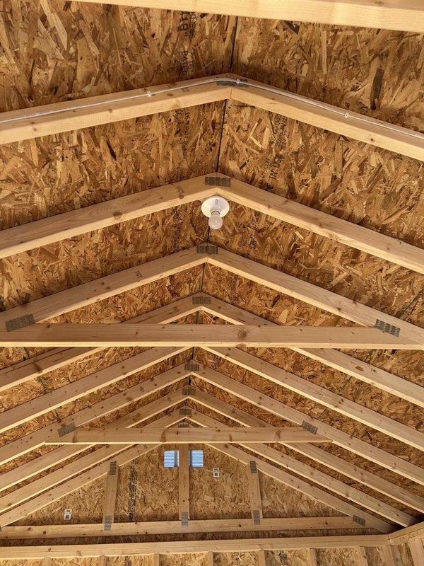 Completed electrical rough-in installation for commercial space under construction, installing GFCI receptacle, standard duplex outlet, single-pole switch, and keyless light fixture with bulb in vaulted ceiling area. All materials stocked and installed per code requirements including SJ cord with male cord cap, with outlets and switching devices properly mounted to exposed framing in preparation for final wall finishing.