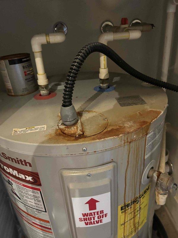 Responded to service call for simultaneous failure of water heater, garbage disposal, and HVAC system. Upon inspection, found A.O. Smith ProMax tank water heater in utility closet exhibiting significant rust corrosion on top surface and active water leakage at base. Identified multiple plumbing connections including PVC supply lines, copper piping, and gas line connection via black flexible corrugated hose. Water staining and pooling around base indicated ongoing leak compromising unit integrity. Assessed electrical supply to utility closet and determined potential circuit issue affecting multiple appliances. Documented corroded water heater condition with extensive orange-brown discoloration across upper lid area and water damage throughout installation area. Evaluated garbage disposal for operational failure in conjunction with other system outages. Provided comprehensive diagnostic assessment and estimate for water heater replacement, garbage disposal repair, and electrical troubles