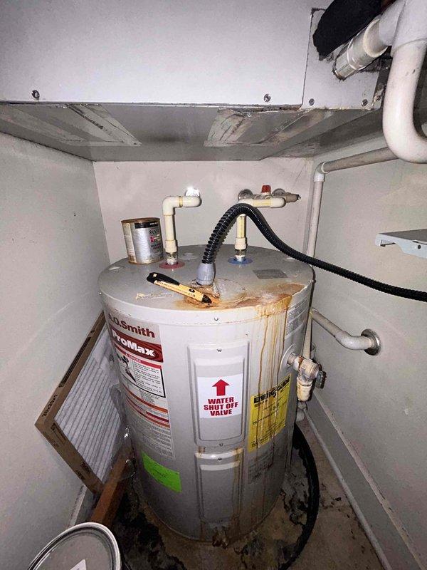 Responded to service call for simultaneous failure of water heater, garbage disposal, and HVAC system. Upon inspection, found A.O. Smith ProMax tank water heater in utility closet exhibiting significant rust corrosion on top surface and active water leakage at base. Identified multiple plumbing connections including PVC supply lines, copper piping, and gas line connection via black flexible corrugated hose. Water staining and pooling around base indicated ongoing leak compromising unit integrity. Assessed electrical supply to utility closet and determined potential circuit issue affecting multiple appliances. Documented corroded water heater condition with extensive orange-brown discoloration across upper lid area and water damage throughout installation area. Evaluated garbage disposal for operational failure in conjunction with other system outages. Provided comprehensive diagnostic assessment and estimate for water heater replacement, garbage disposal repair, and electrical troubles