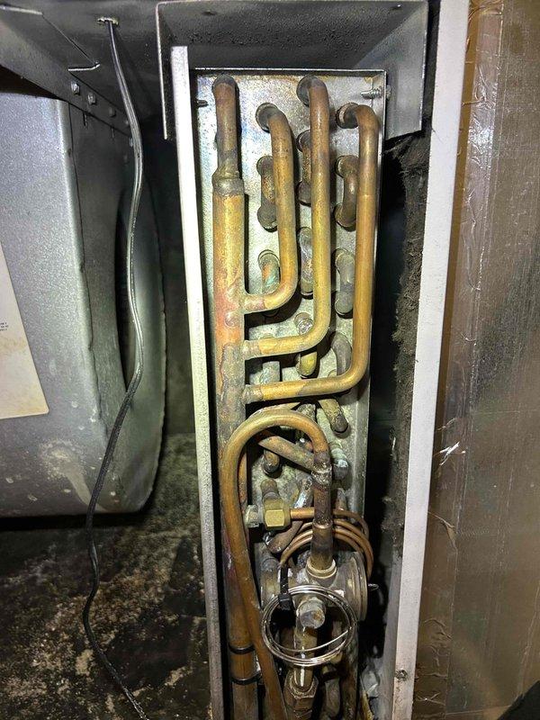 Responded to no cooling complaint on older electric HVAC system with indoor temperature reading 73°F while thermostat set to 68°F. Upon arrival, confirmed air handler blower operation but no refrigeration cycle. Accessed utility closet-mounted air handler and inspected system components. Observed significant age-related deterioration including oxidized copper tubing with visible patina formation and general wear consistent with 10+ year old equipment. Performed diagnostic evaluation of refrigeration system, electrical components, and capacitor function to determine root cause of cooling failure and provided repair recommendations to restore system operation.
