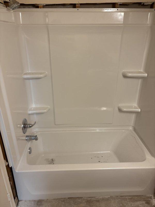 Completed installation of 30x60 white left-hand bathtub and shower surround on second floor vacant unit. Removed existing tile and knockdown walls, installed new knockdown wall system with one-piece fiberglass surround featuring integrated corner shelving. Installed Delta chrome body faucets with cross-handle trim, new shower valve assembly, Delta chrome tub spout, and shower arm with head. Completed Watco waste and overflow installation with all necessary water supply and drain connections. Work area cleaned and debris removed upon completion.
