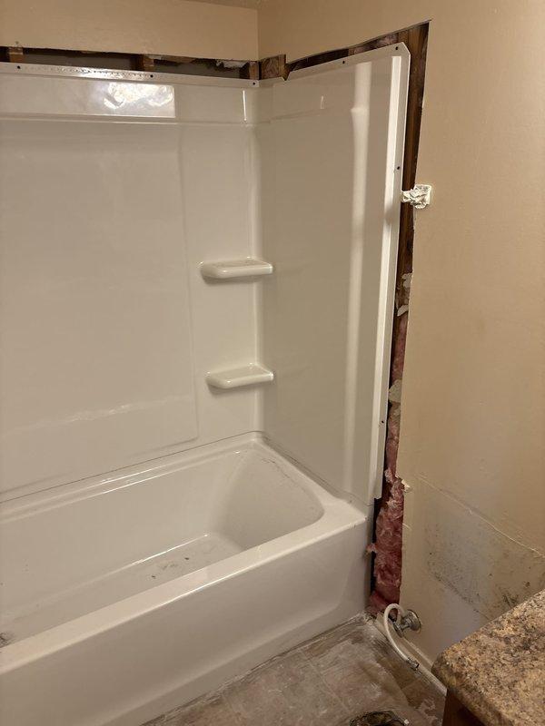 Completed installation of 30x60 white left-hand bathtub and shower surround on second floor vacant unit. Removed existing tile and knockdown walls, installed new knockdown wall system with one-piece fiberglass surround featuring integrated corner shelving. Installed Delta chrome body faucets with cross-handle trim, new shower valve assembly, Delta chrome tub spout, and shower arm with head. Completed Watco waste and overflow installation with all necessary water supply and drain connections. Work area cleaned and debris removed upon completion.