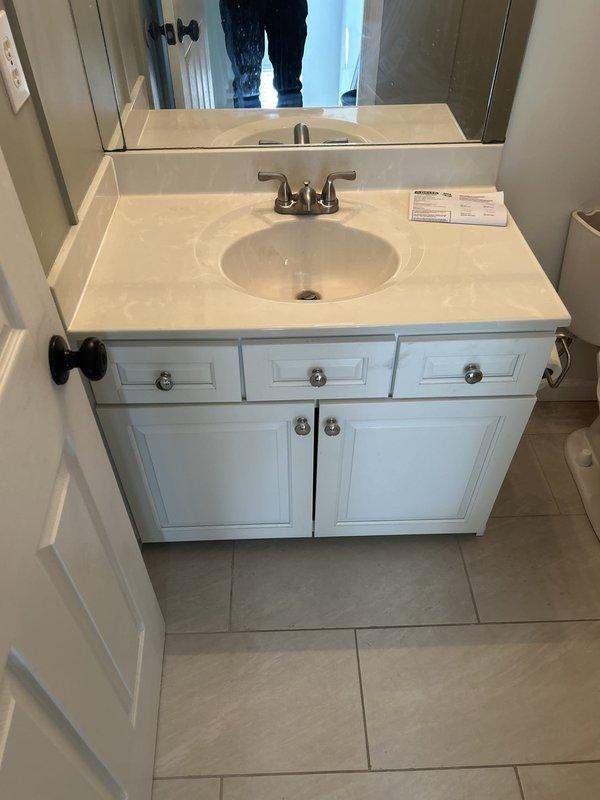 Replaced customer-supplied Delta lavatory faucet with 4-inch spread configuration on bathroom vanity. The new brushed nickel two-handle faucet was successfully installed on the vanity's integrated oval sink basin, with all connections properly sealed and tested for leaks.